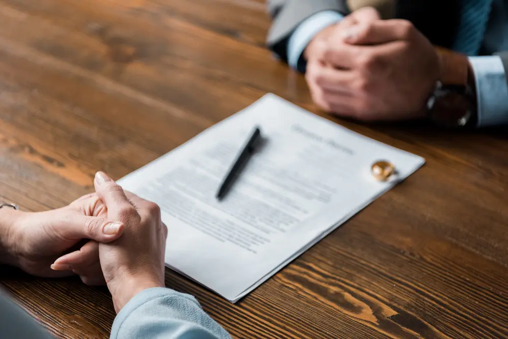 Two people sitting at a table with a divorce agreement between them.
