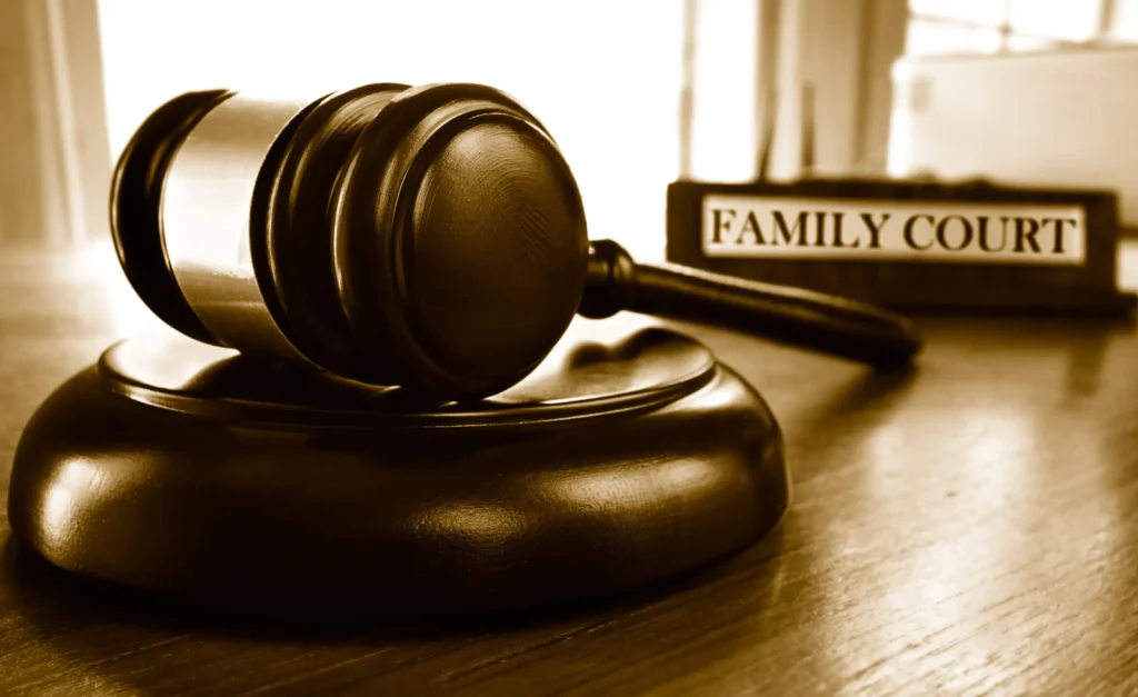 A gavel sits on a desk with a plaque that says family court in the background.