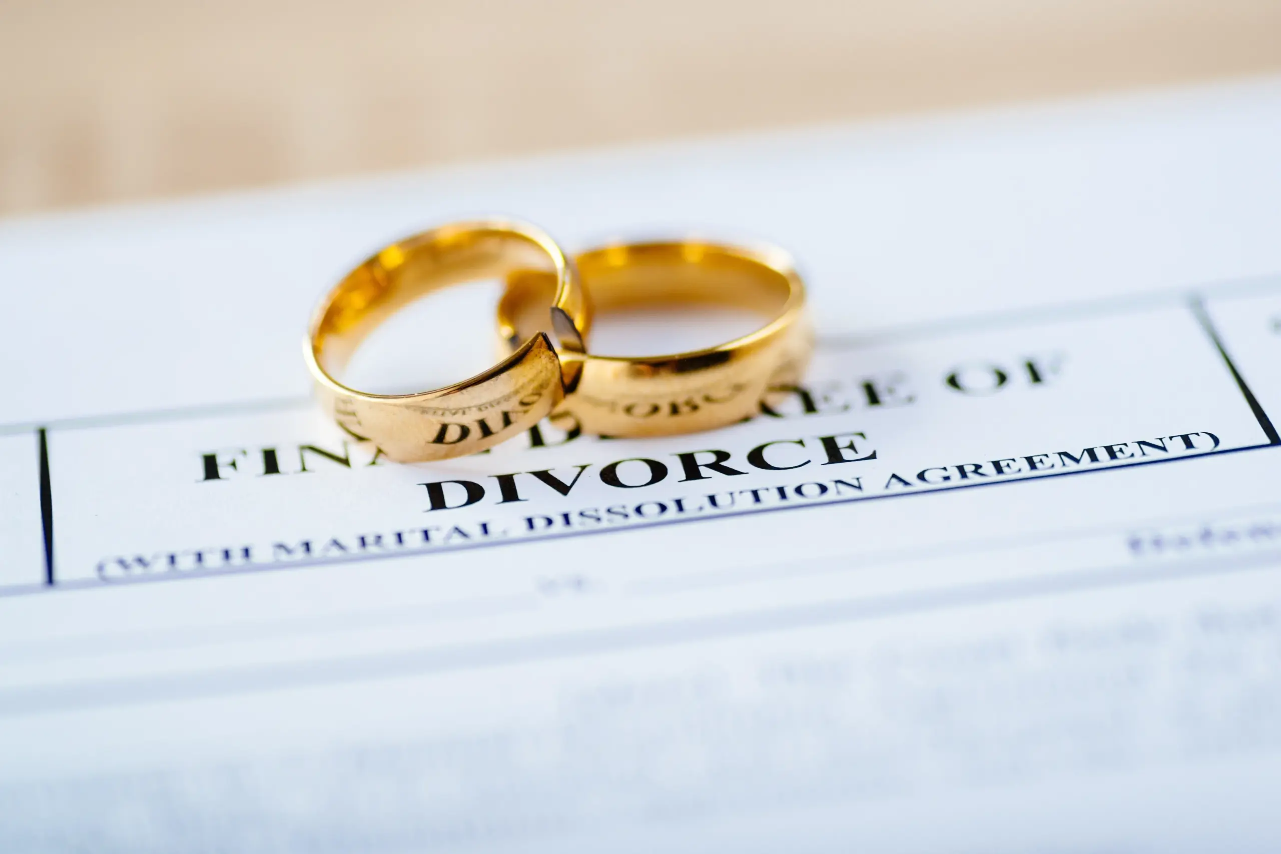 Paperwork that says divorce with two wedding rings.