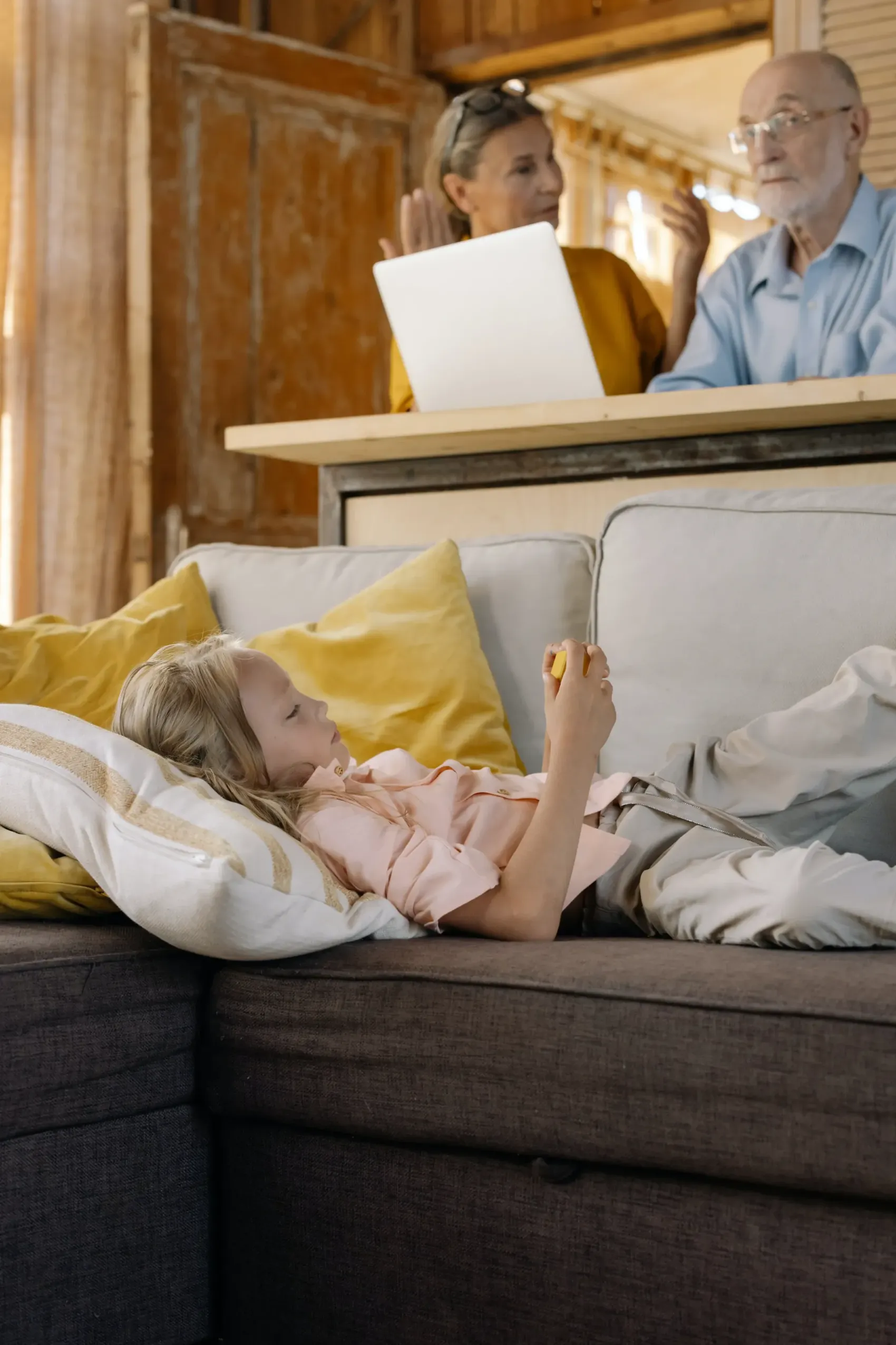 Grandparents are talking with a grandchild laying on the couch.