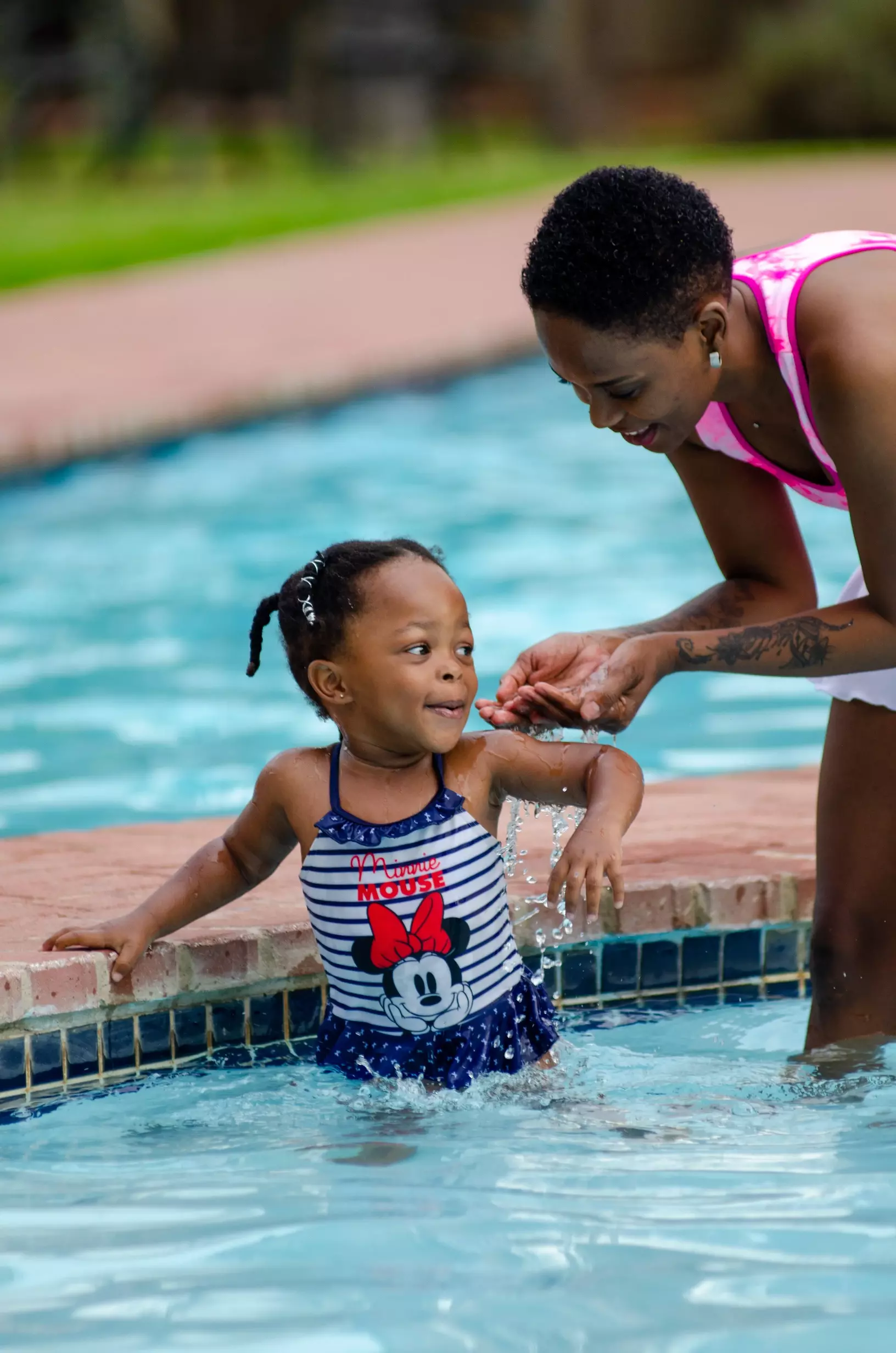 A mom playing with her child in a pool.
