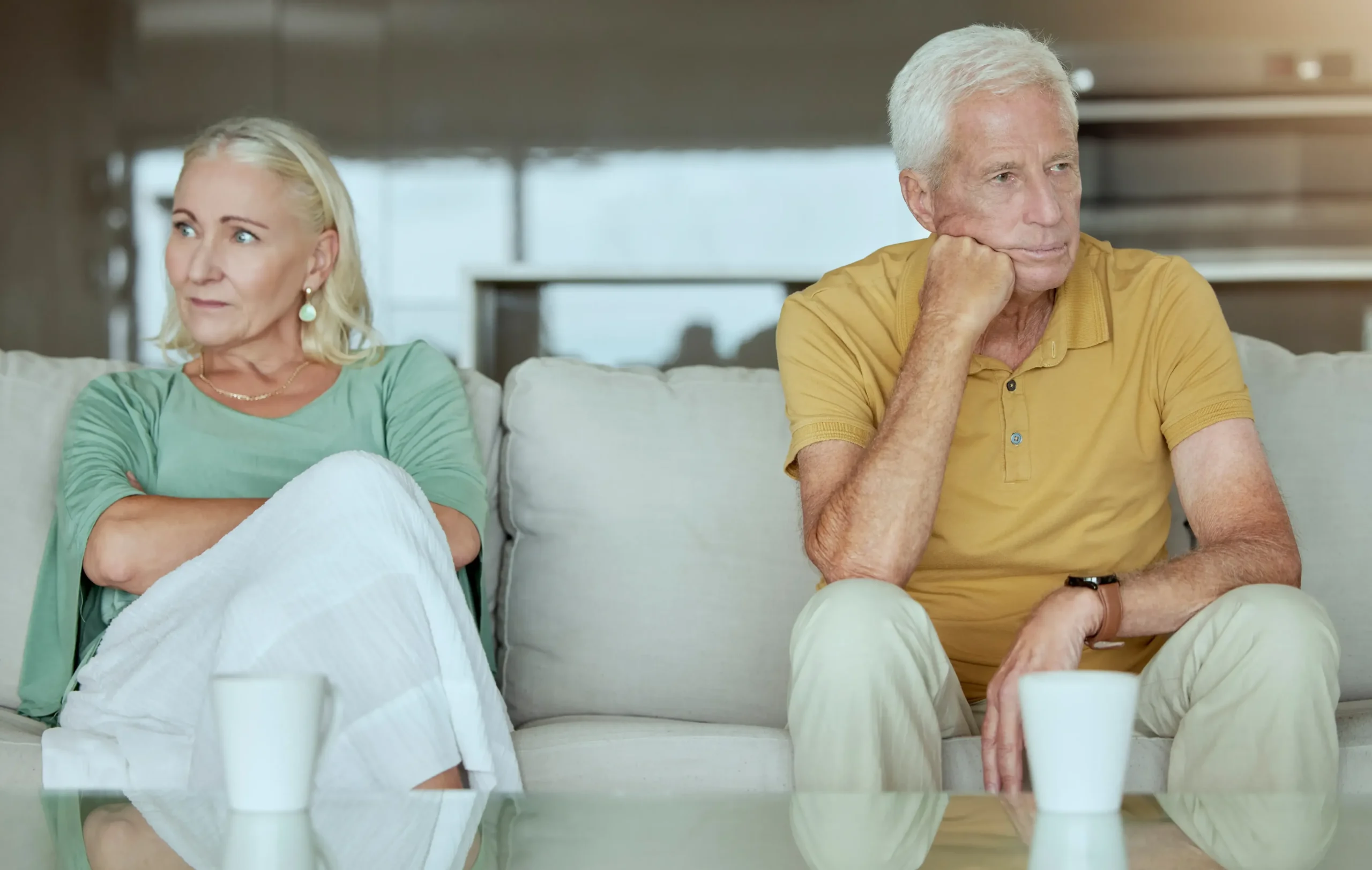 An older couple sitting next to each other looking unhappy.
