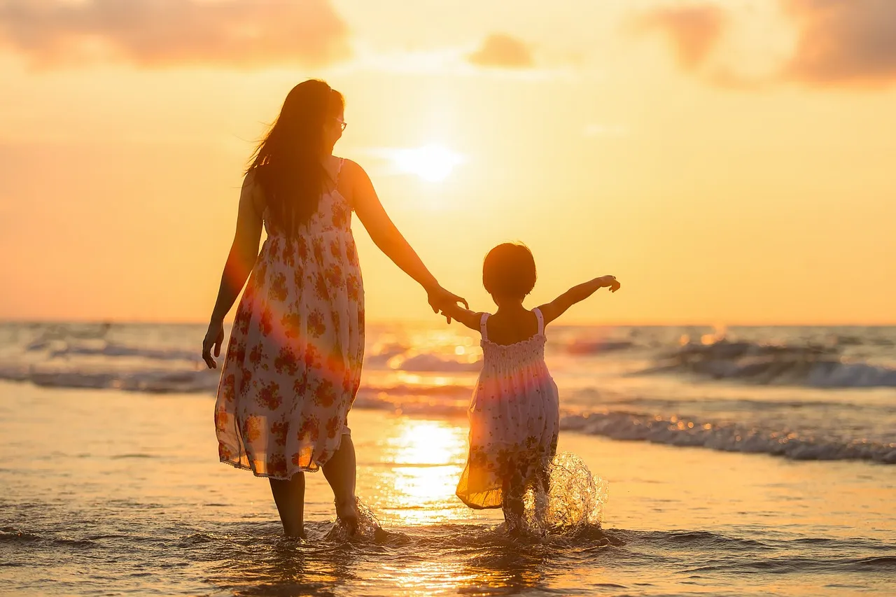 A mom playing with her child in the ocean.