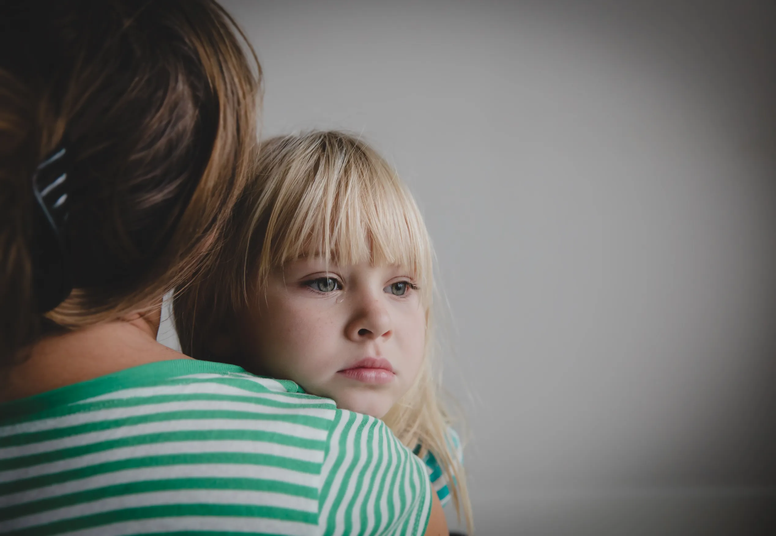 Little girl looking over her mother's shoulder. Divorce in Austin, TX.