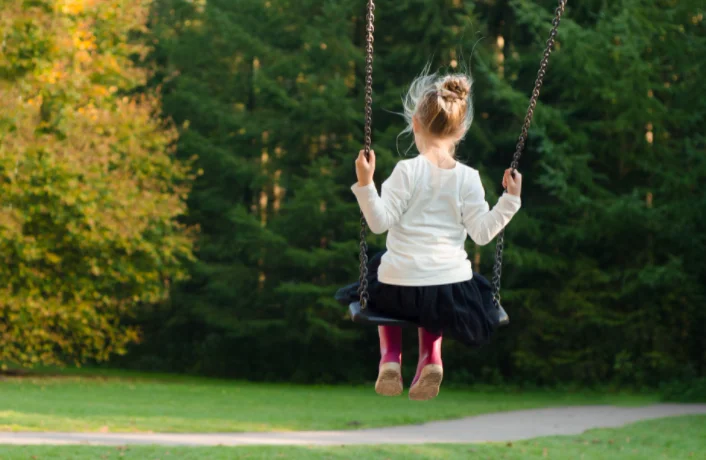 Child sitting on a swing.