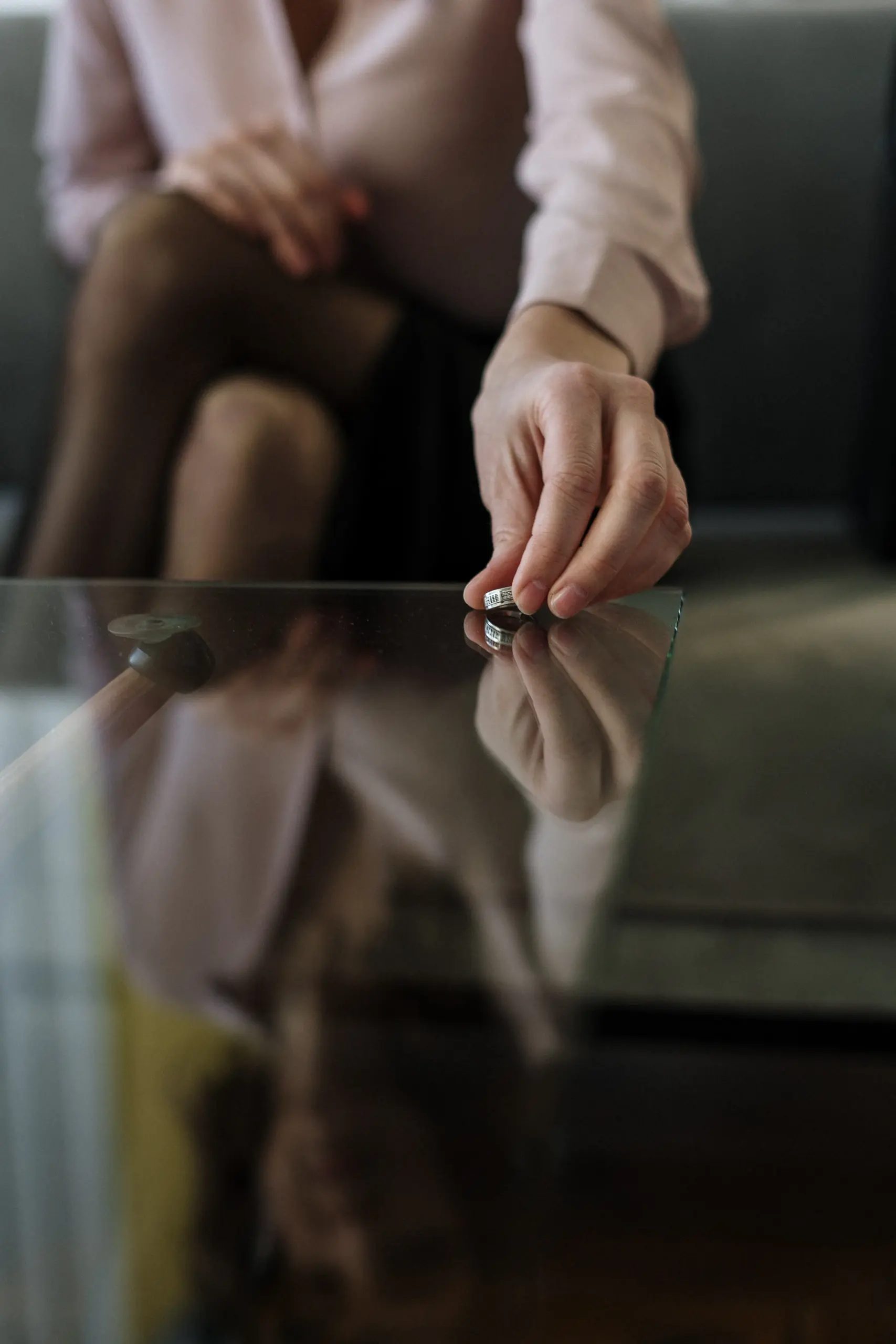 A woman laying her ring on a table.