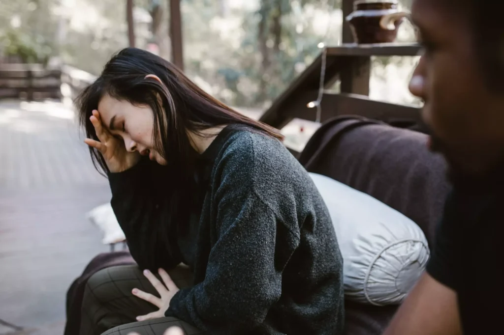 A woman sits distraught after an argument with a man.